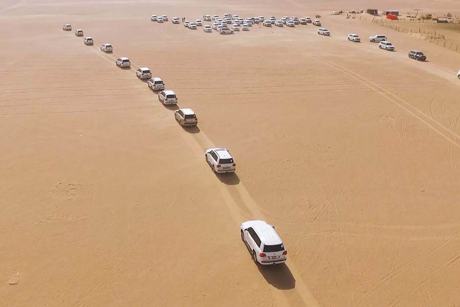 Convoy of 4x4 vehicles crossing the desert dunes